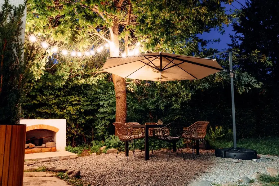 Outdoor dining area with a fireplace and string lights in the evening