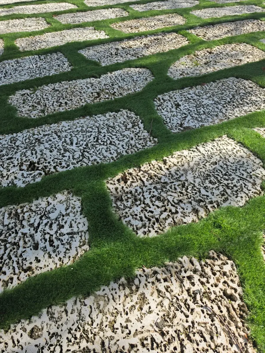 Crew member brushing newly installed artificial turf beside a brick border