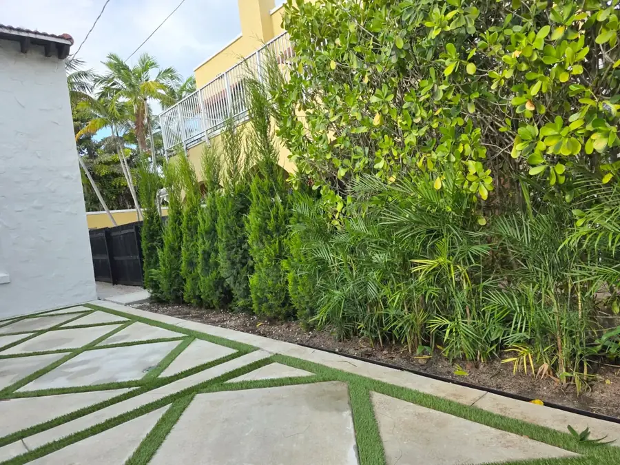 Gate and fence along a residential driveway with a lawn and palms